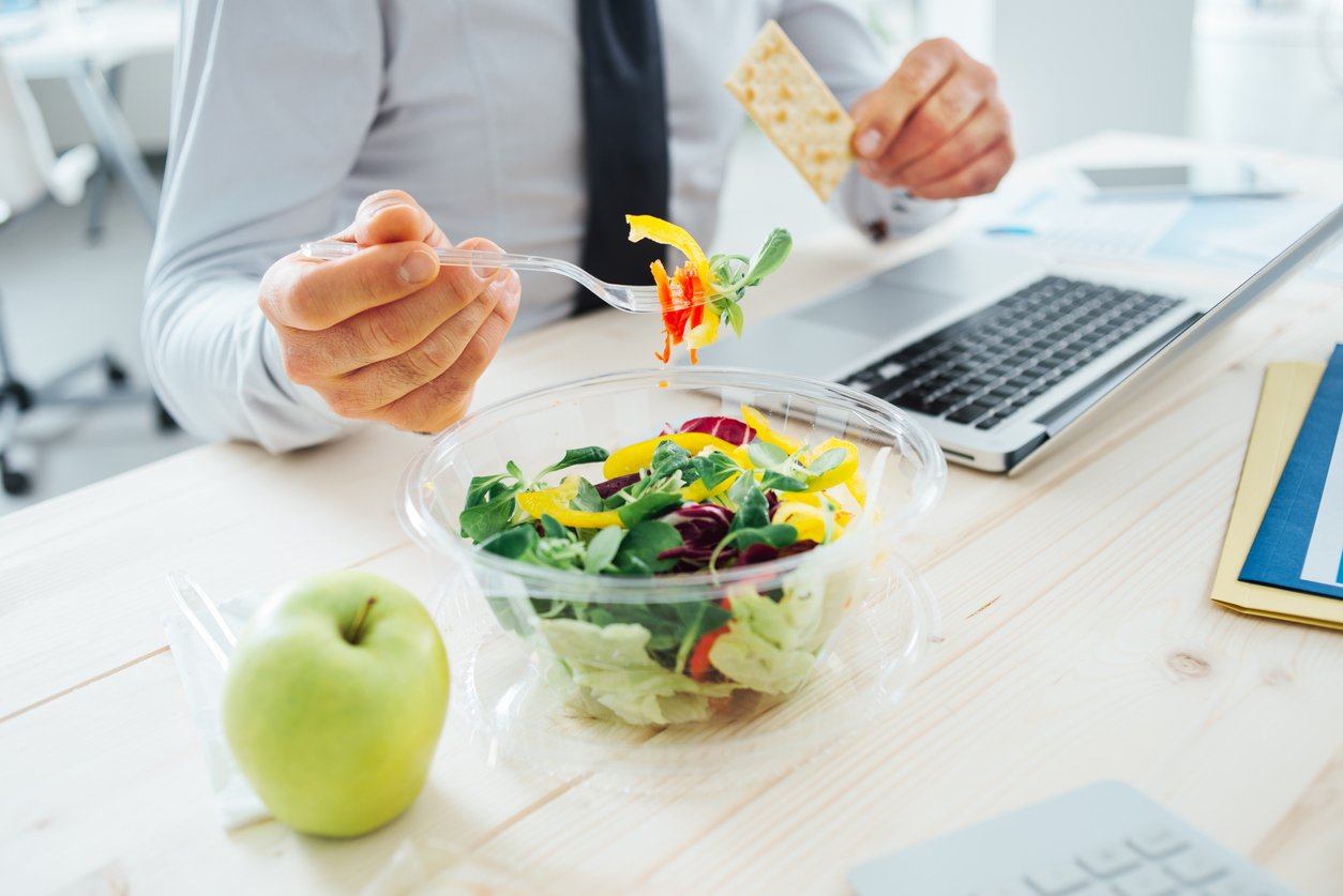 businessman eating healthily with salad, apple and crackers