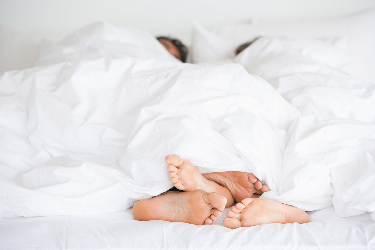 cozy couple sleep routine with feet sticking out from covers