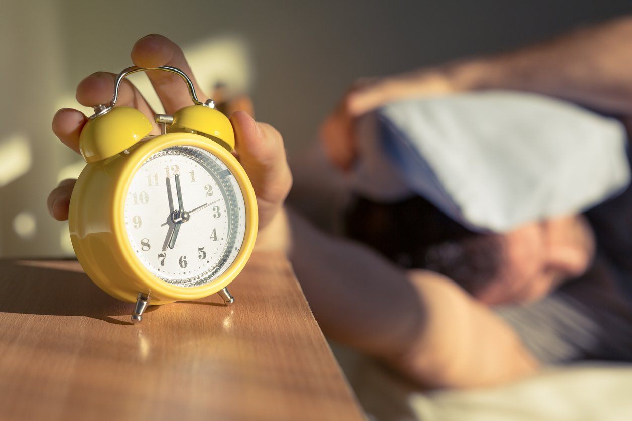 Man in bed learning to wake up on time without hitting snooze