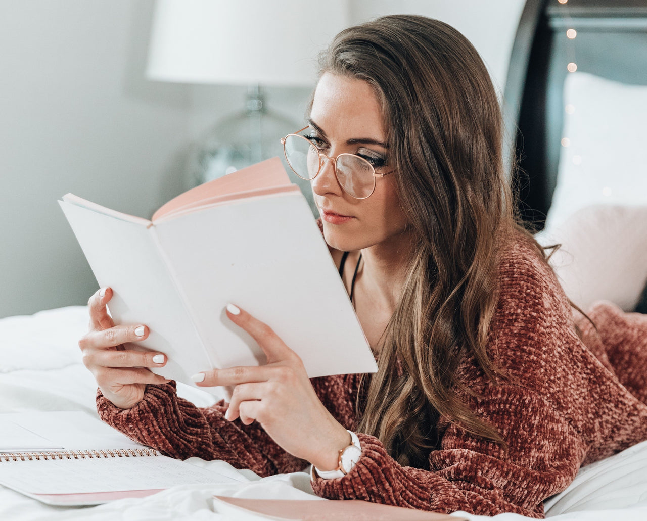 woman reading journaling in bed