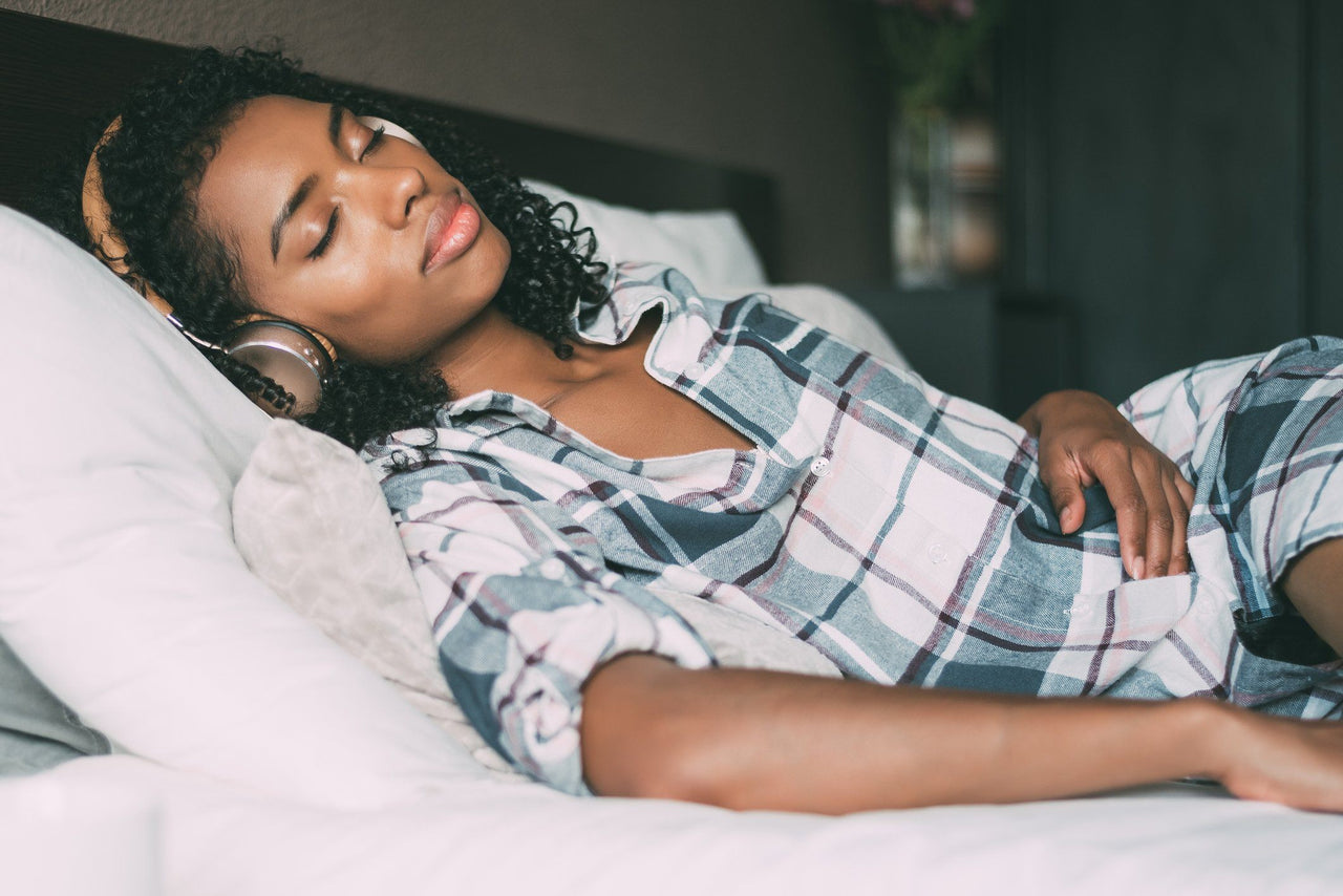 woman sleeping in bed with headphones playing binaural beats