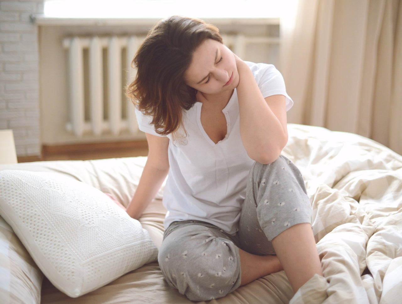 woman waking up with sore neck from poor sleeping position