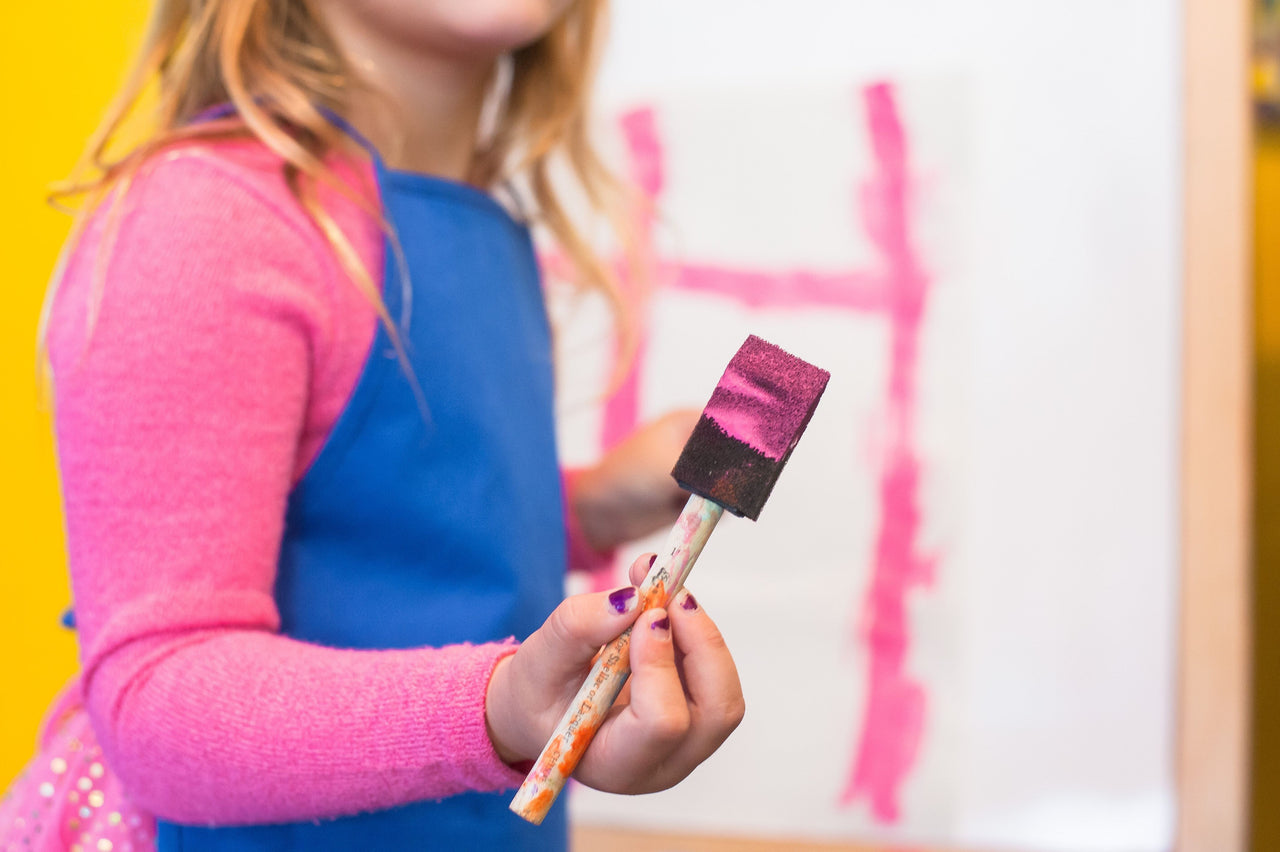 young girl painting with sponge brush