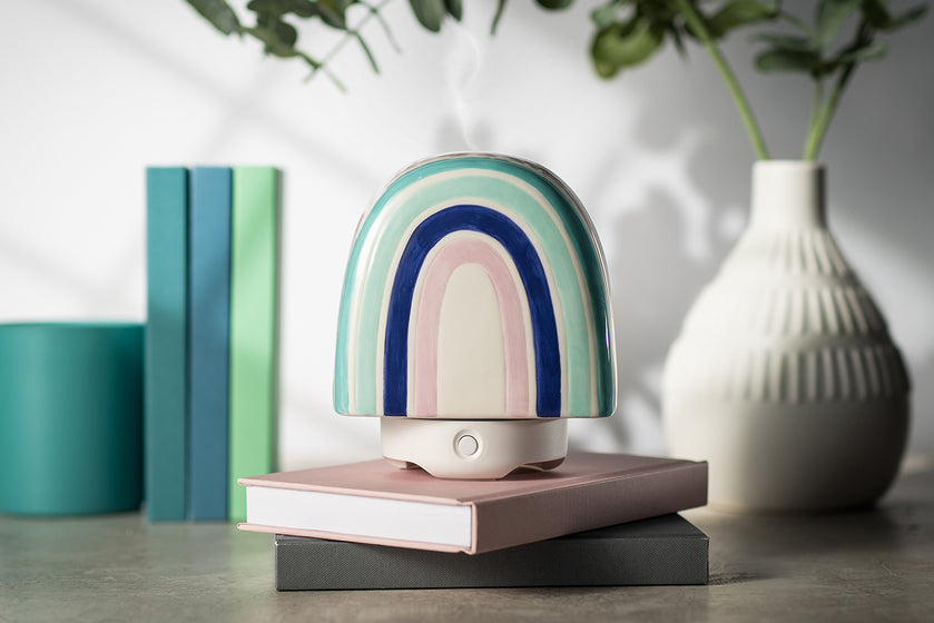 The woolzies rainbow glass diffuser sitting atop two stacked books