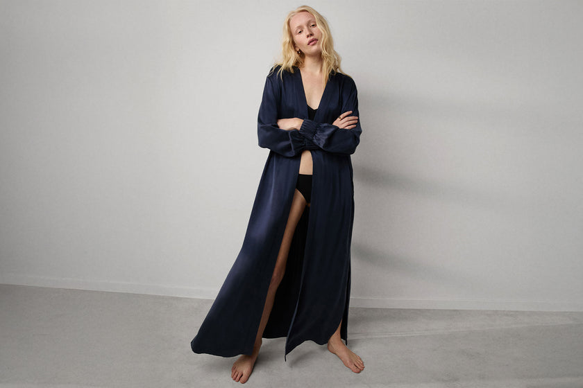 Woman wearing a long navy blue robe against a plain background