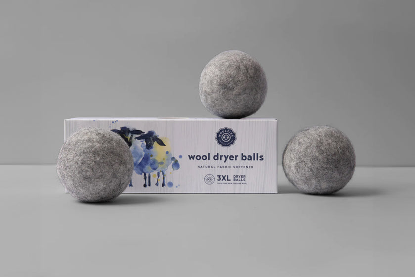 grey wool dryer balls on top of their packaging box