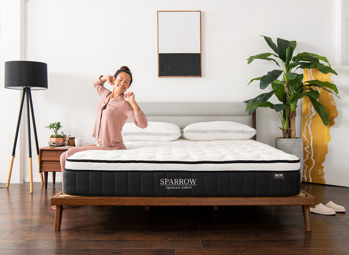 Woman stretching on a Sparrow mattress in a bedroom setting