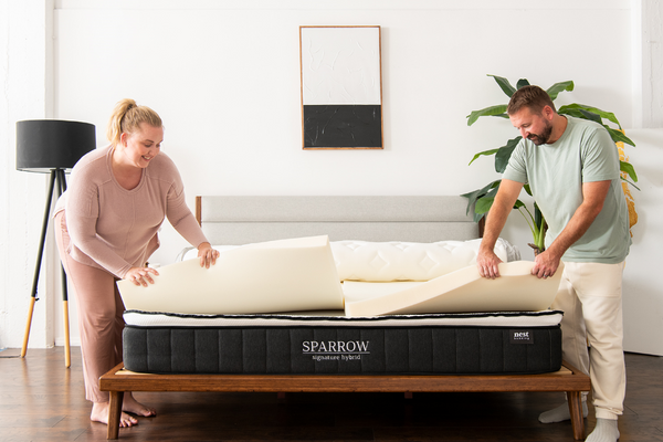 A man and woman opening up the Sparrow mattress to reveal the layers inside the mattress.