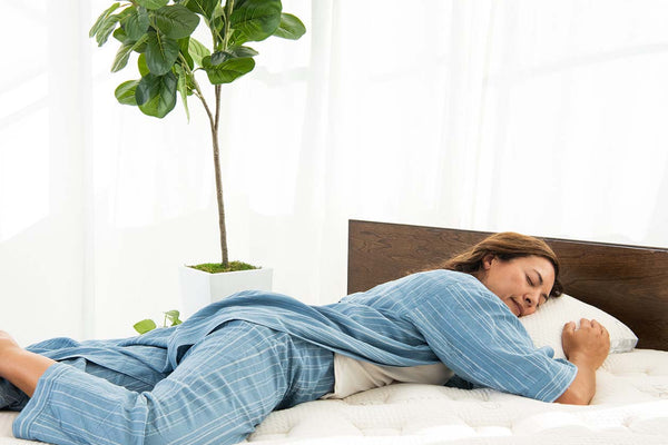 Woman lying down on mattress with head on pillow