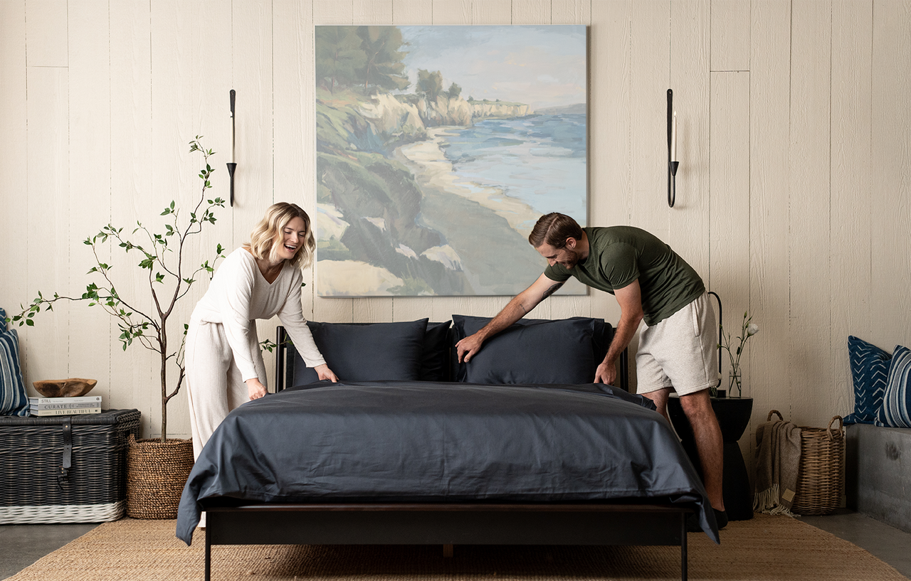couple making bed, dark grey bedding, slate organic cotton sateen, bed set, duvet set, sheet set, bedroom scene