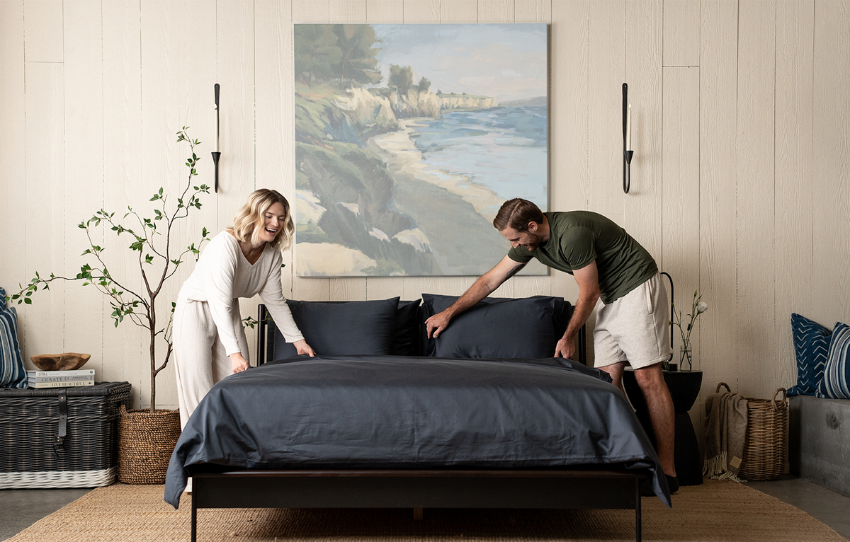 couple making bed, dark grey bedding, slate organic cotton sateen, bed set, duvet set, sheet set, bedroom scene