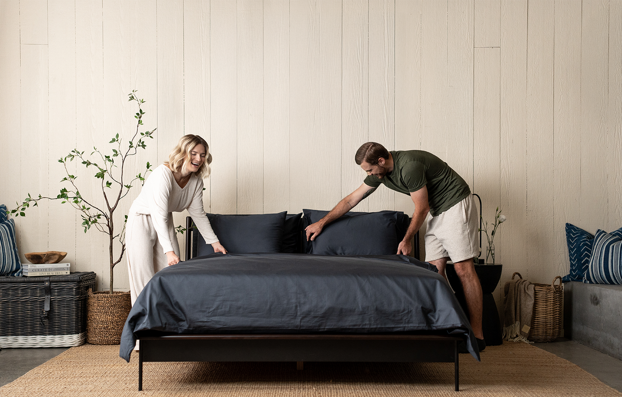 couple making bed, dark grey bedding, slate organic cotton sateen, bed set, duvet set, sheet set, bedroom scene