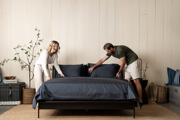 couple making bed, dark grey bedding, slate organic cotton sateen, bed set, duvet set, sheet set, bedroom scene