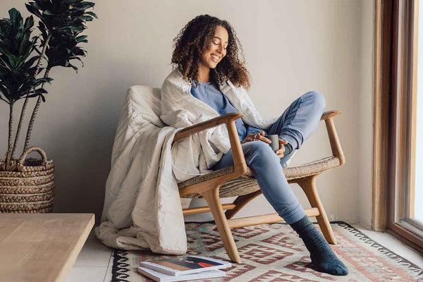 Woman reading in chair looking cozy and comfy