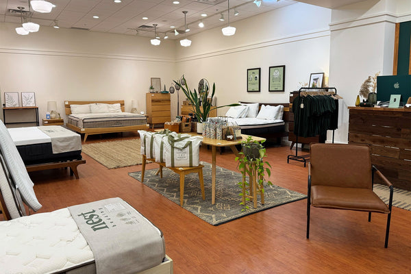 The inside of the Nest Bedding Chico, California store with various beds, chairs, and decor items on a wooden floor.