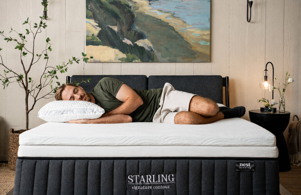 bedroom scene, man laying comfortably on side on top of the Cooling Topper and Easy Breather Pillow