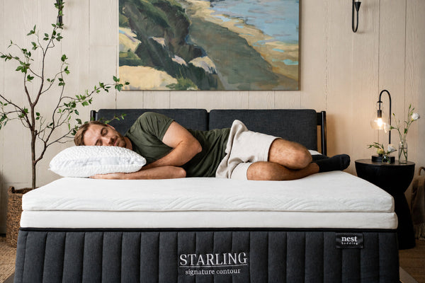 bedroom scene, man laying comfortably on side on top of the Cooling Topper and Easy Breather Pillow