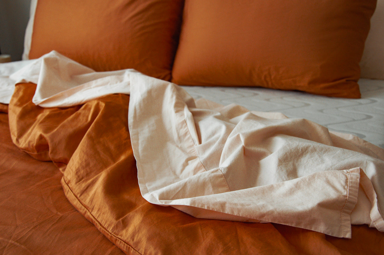 a closeup photograph of nest bedding organic cotton peach sheets and the terracotta duvet