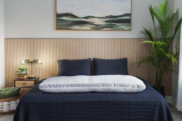 A moody bedroom with dark slate bamboo bedding and a king size easy breather body pillow displayed across the foot of bed