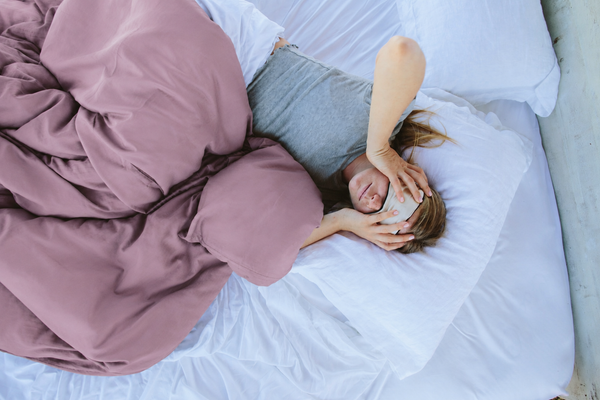 Person lying on a mattress while evaluating comfort and pillow support during the first weeks of a new bed.