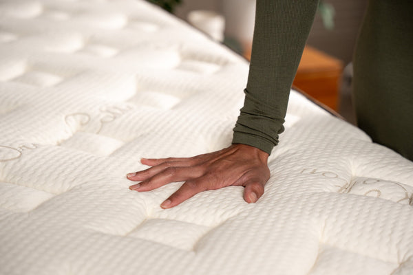 Hand pressing down onto the Owl Natural Hybrid mattress organic cotton cover material