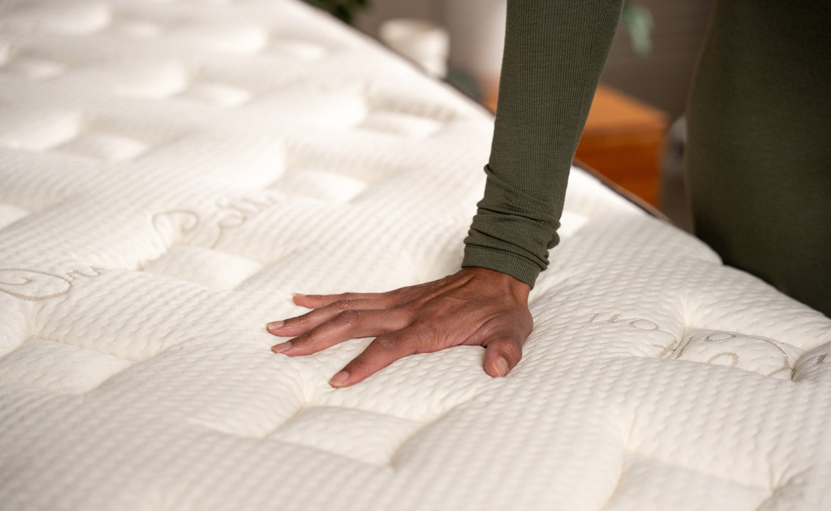 Hand pressing down onto the Owl Natural Hybrid mattress organic cotton cover material