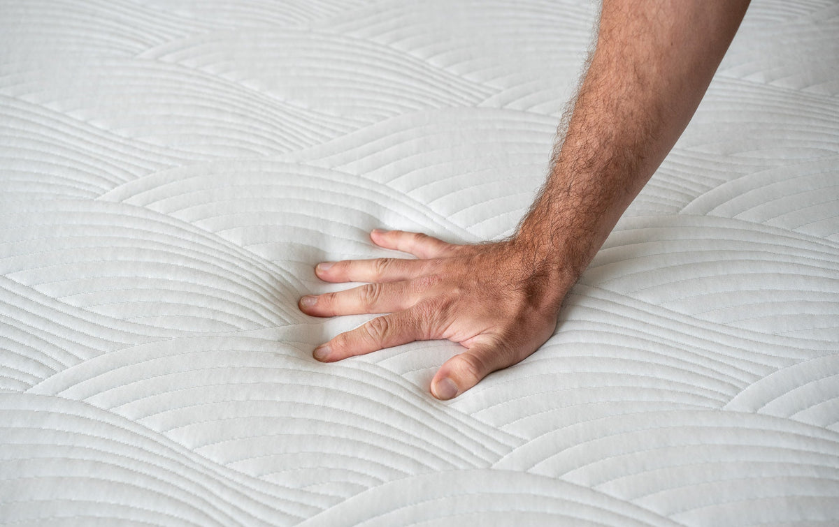 a man's hand pushing into the starling mattress thermic phase change cover