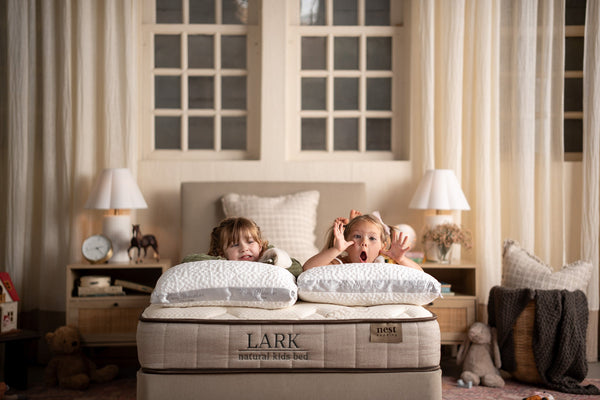 Two girls making silly faces on the lark natural kids bed and easy breather jr pillows