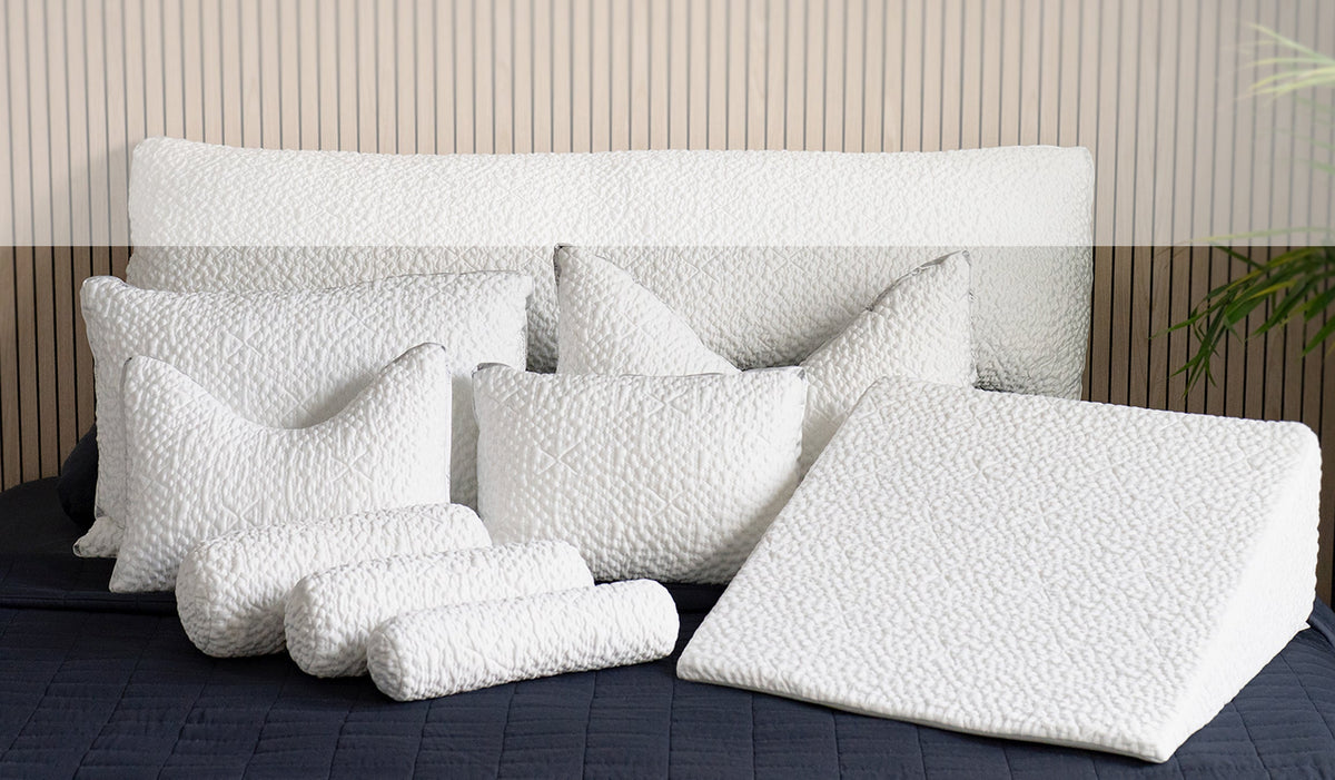 Set of white pillows on a bed with a wooden headboard.