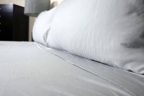 a closeup photo of light grey bamboo sheets on a bed