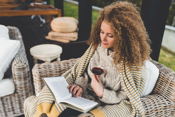 woman who can't sleep is reading and drinking glass of wine