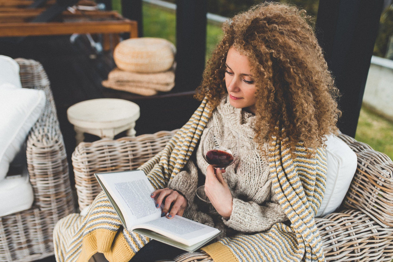 woman who can't sleep is reading and drinking glass of wine
