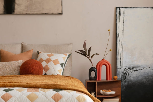 Cozy bedroom with a bed, pillows, and a side table with decorative items.