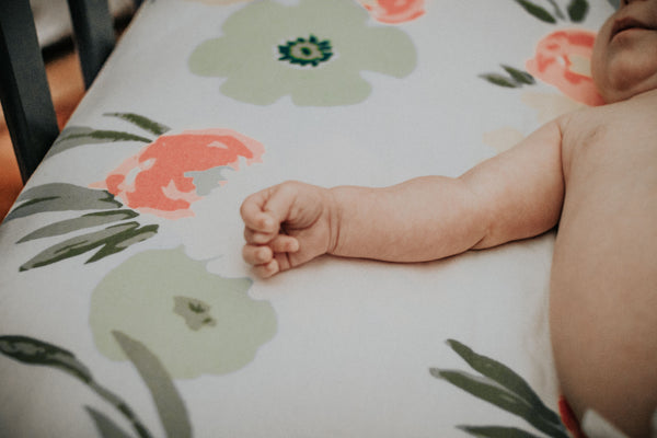 baby in nursery sleeping on crib with flower designs