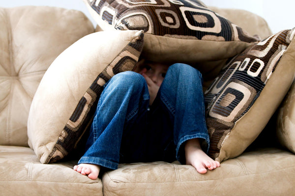 Kid tucked inside a pile of pillows