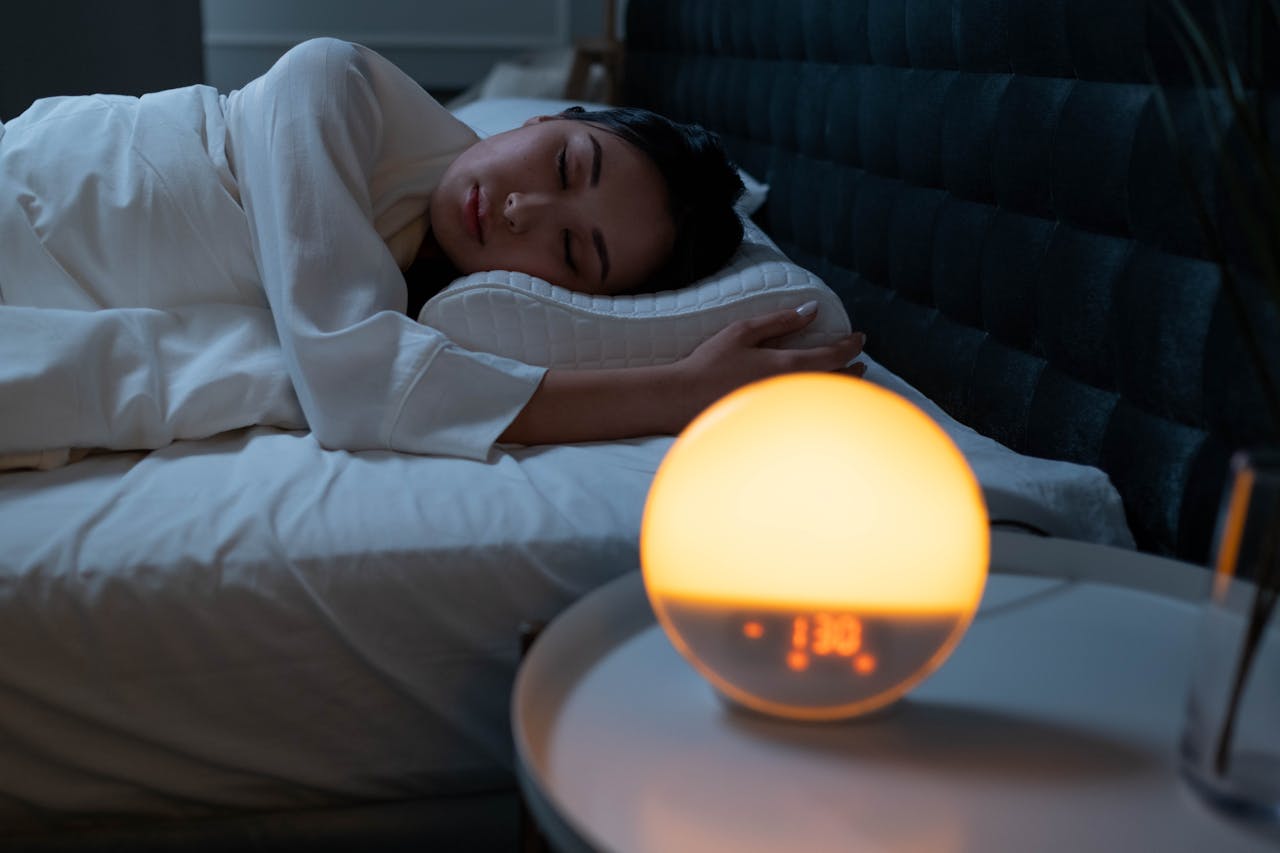 Person sleeping in bed with a glowing night light on a nightstand.