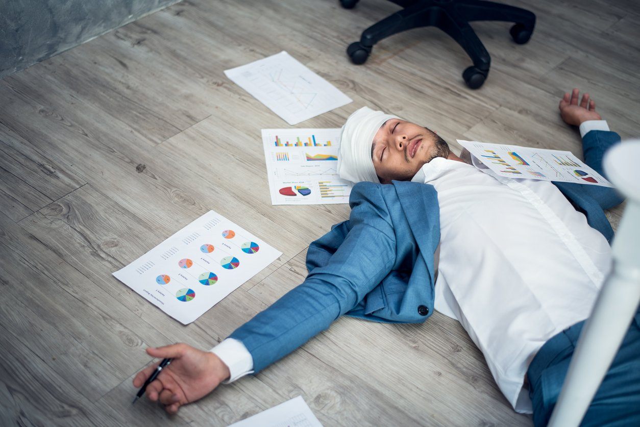 businessman sleeping on floor next to business reports and charts