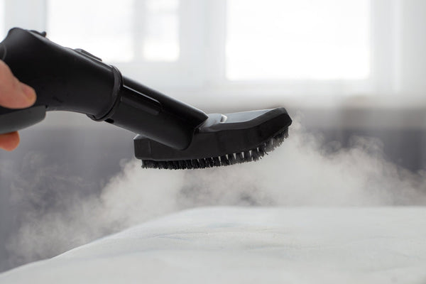 A steam cleaner hovering over a mattress