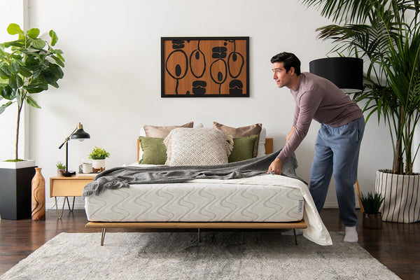 A man adjusting the bedding on the Quail mattress.