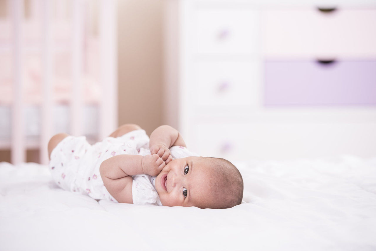 excited baby girl lying in crib in nursery for better sleep
