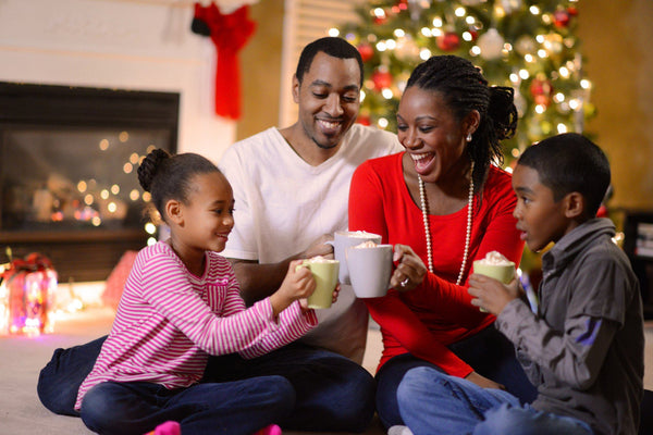 family drinking hot chocolate by Christmas tree