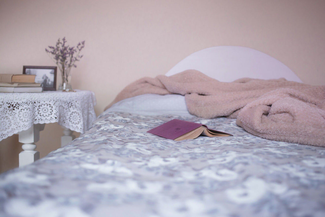 A book laying face down on top of sheets and a bed