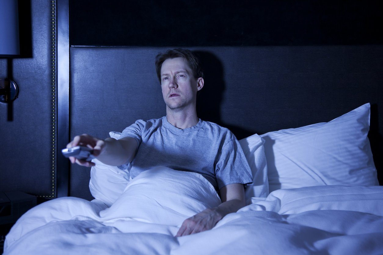 A man watches tv before bed, mixing electronics and sleep