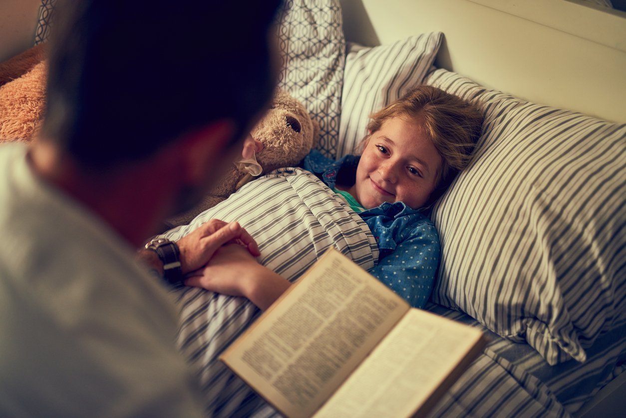 Dad reading bedtime story to daughter