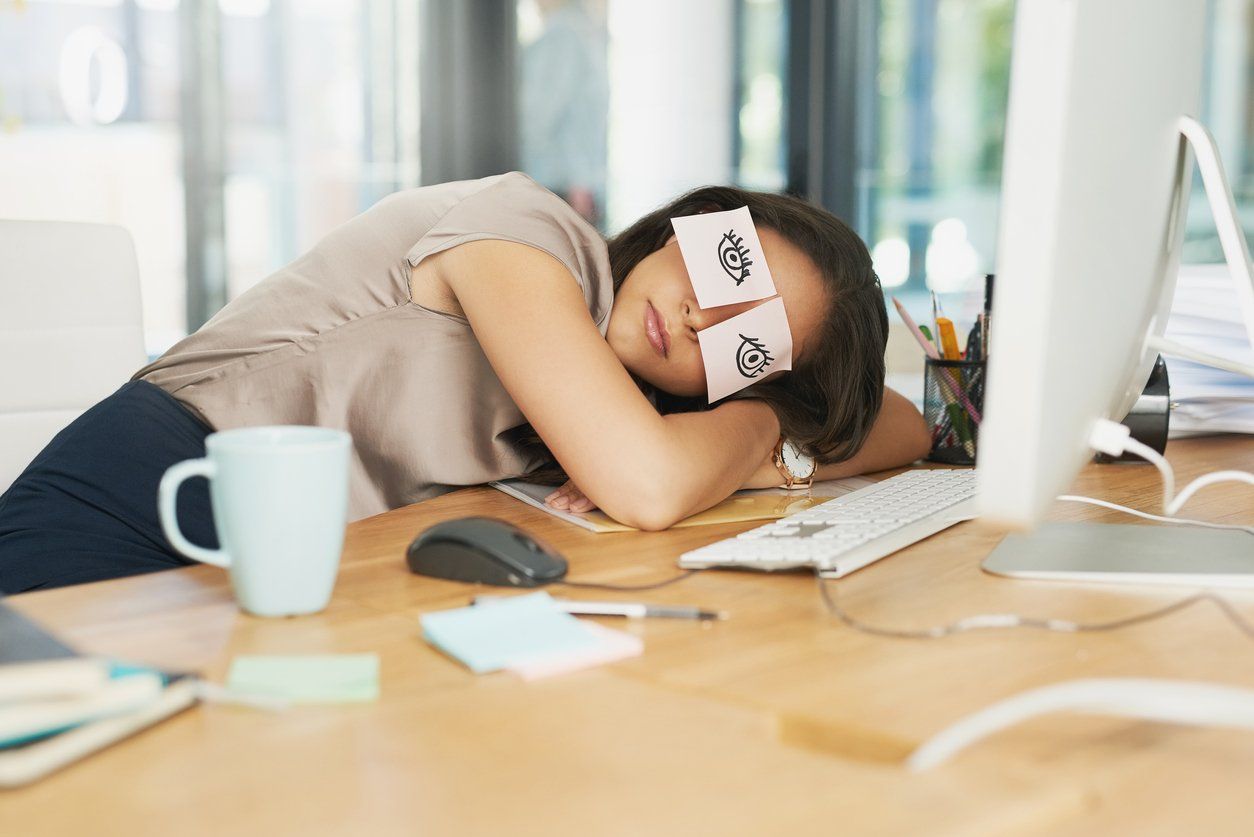 Businesswoman sleeping at desk after trying to stay awake at work without caffeine