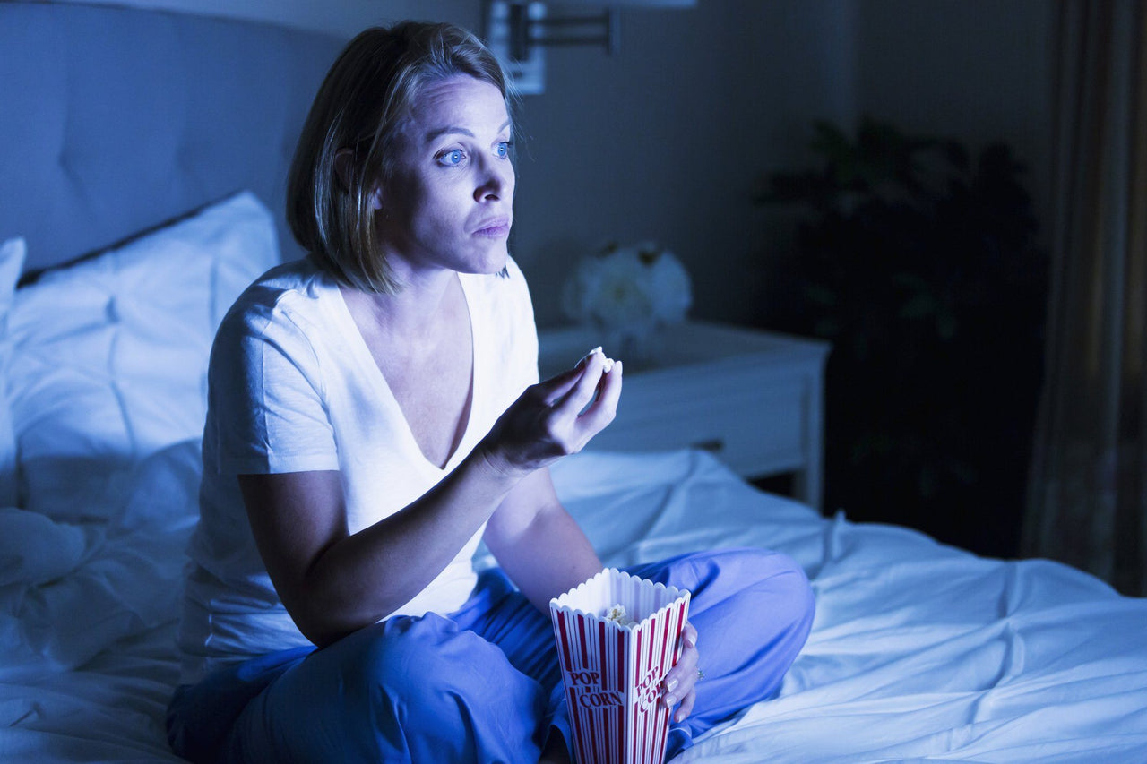 Woman eating popcorn exploring what to watch when you can't sleep