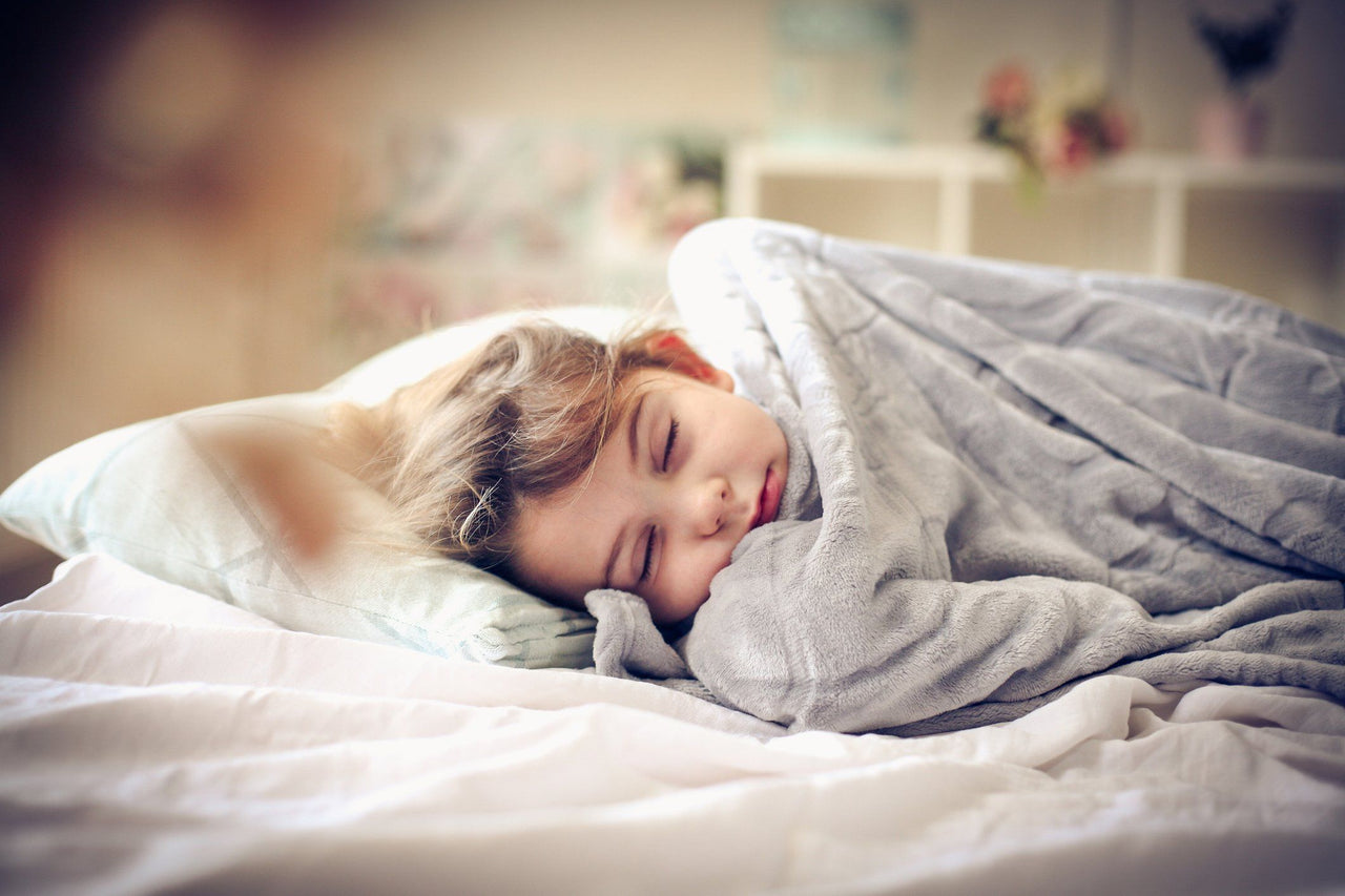 little girl sleeping under weighted blankets