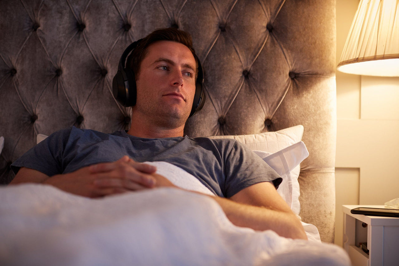 man listening to podcast in bed