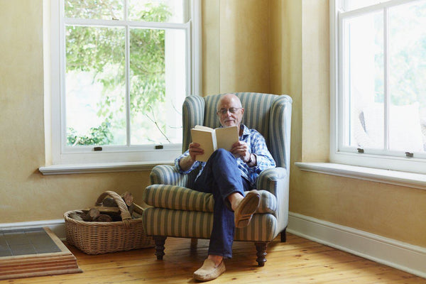 man reading a book in a corner lounge chair