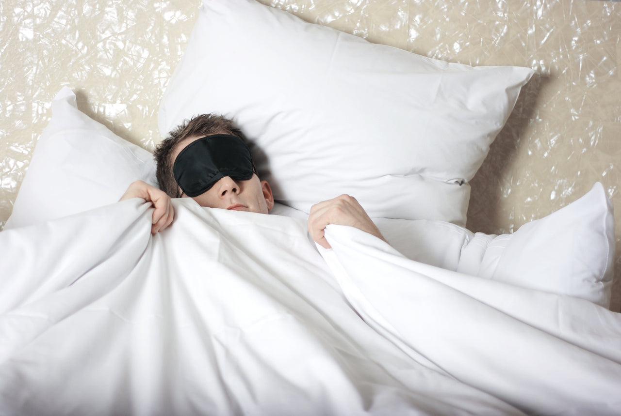 man wearing sleep mask in bed for better sleep on a budget